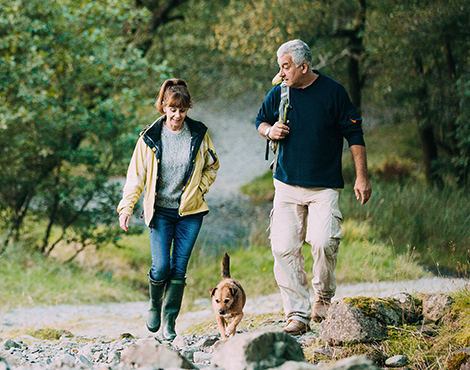 Woman and man hiking through trails with their dog